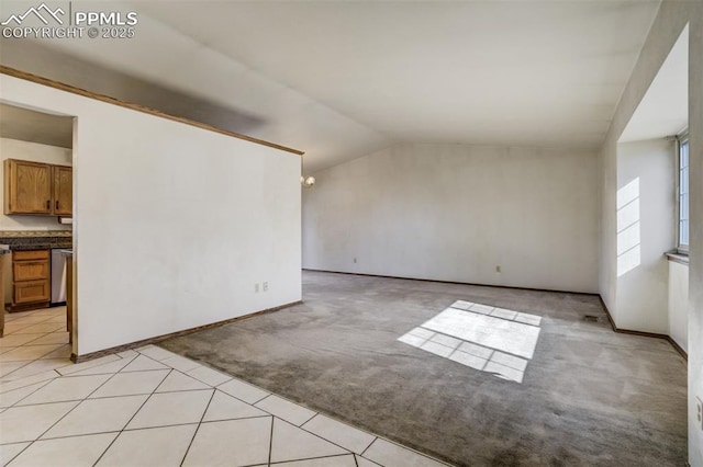 unfurnished room with light carpet, light tile patterned floors, lofted ceiling, and baseboards