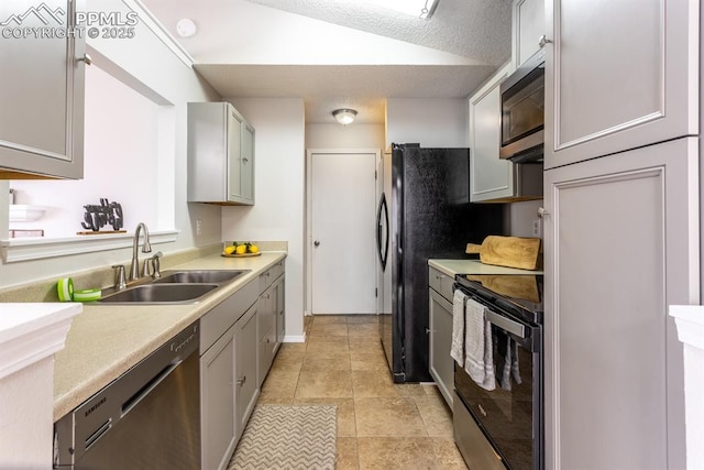 kitchen featuring light tile patterned floors, stainless steel appliances, light countertops, a sink, and a textured ceiling