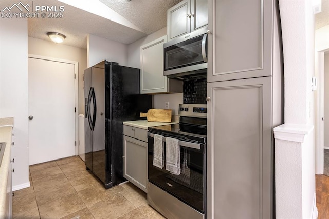 kitchen featuring a textured ceiling, stainless steel appliances, light countertops, and gray cabinetry