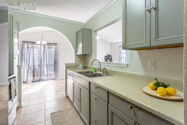 kitchen with dishwasher, light countertops, a textured ceiling, a sink, and light tile patterned flooring