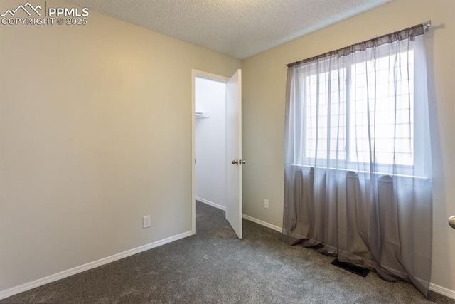 carpeted spare room featuring visible vents, baseboards, and a textured ceiling