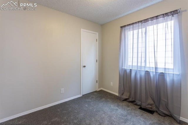 spare room featuring carpet, visible vents, baseboards, and a textured ceiling