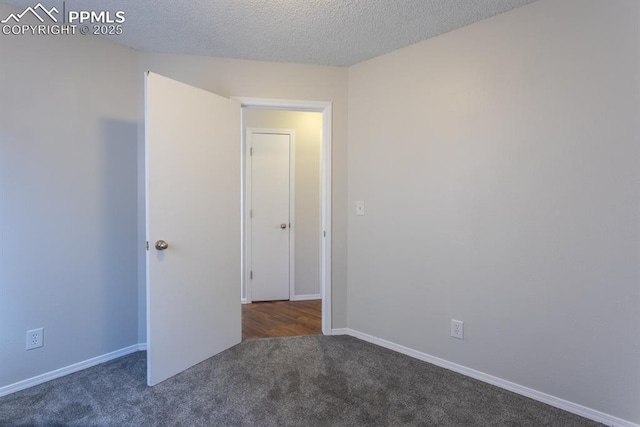 carpeted empty room with a textured ceiling and baseboards