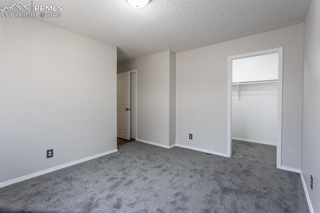 unfurnished bedroom featuring a walk in closet, carpet, and baseboards