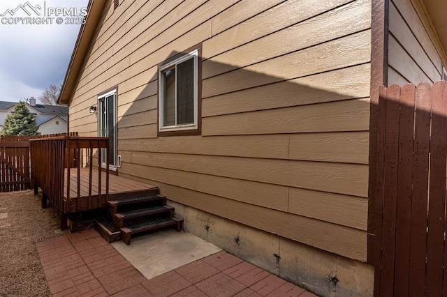 view of side of home with fence, a patio, and a wooden deck