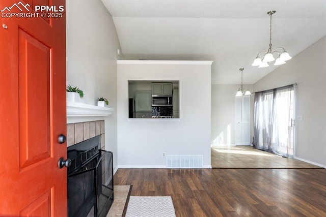 foyer featuring a fireplace, lofted ceiling, visible vents, an inviting chandelier, and dark wood-type flooring