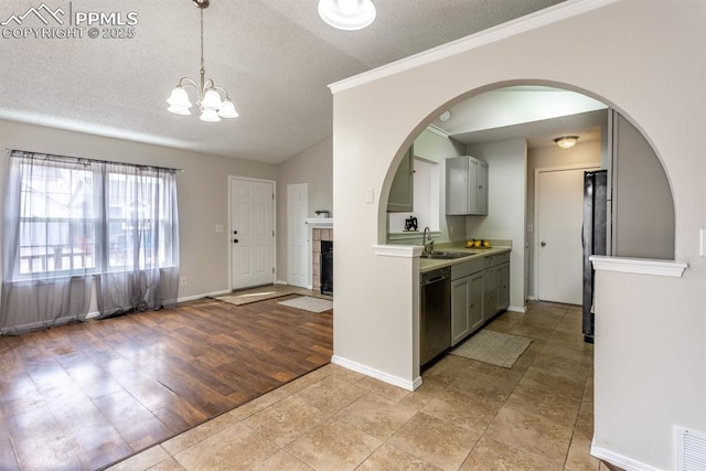 kitchen featuring black refrigerator, gray cabinetry, a sink, and stainless steel dishwasher