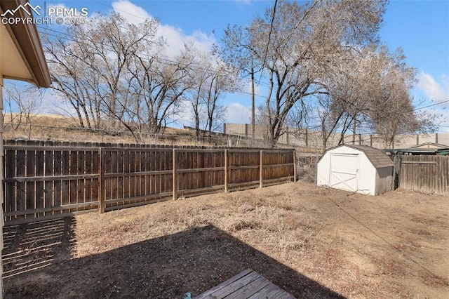 view of yard with a storage shed, a fenced backyard, and an outbuilding