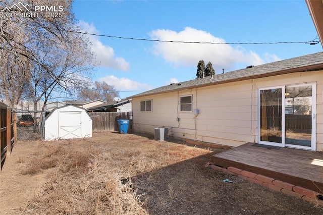 rear view of property featuring a fenced backyard, central air condition unit, an outdoor structure, a wooden deck, and a shed