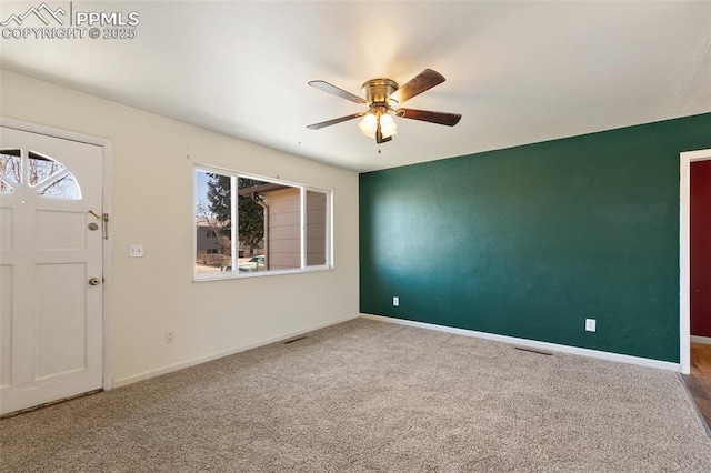 carpeted foyer entrance with ceiling fan, visible vents, and baseboards