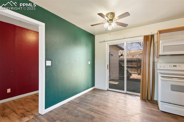 unfurnished dining area featuring a textured wall, wood finished floors, and baseboards