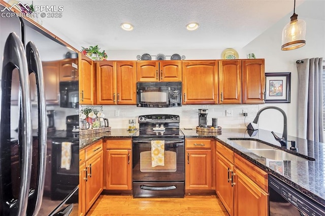 kitchen featuring black appliances, dark stone countertops, tasteful backsplash, and a sink