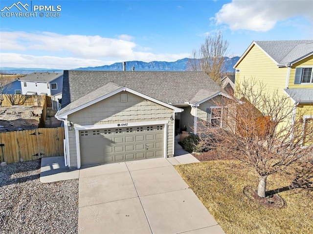 view of front of home featuring fence, roof with shingles, concrete driveway, a garage, and a mountain view