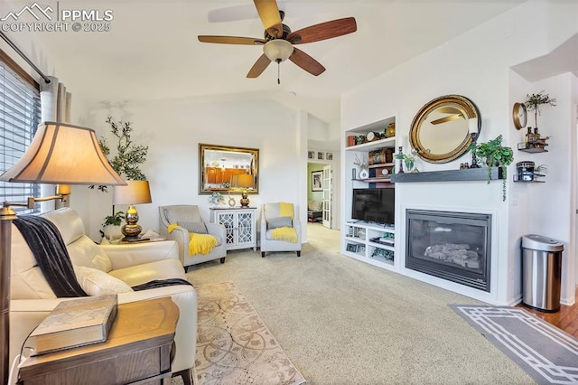 living room with built in features, a ceiling fan, carpet floors, lofted ceiling, and a glass covered fireplace