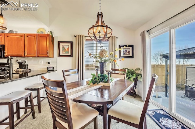 dining room featuring plenty of natural light, a notable chandelier, and lofted ceiling