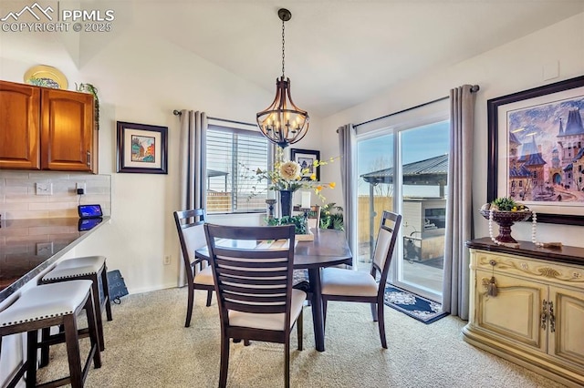 dining area featuring a notable chandelier, light colored carpet, and vaulted ceiling