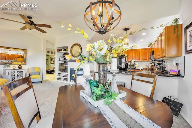 carpeted dining room featuring built in shelves, ceiling fan with notable chandelier, and vaulted ceiling