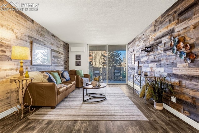 living area featuring wooden walls, baseboards, wood finished floors, a textured ceiling, and a wall mounted AC