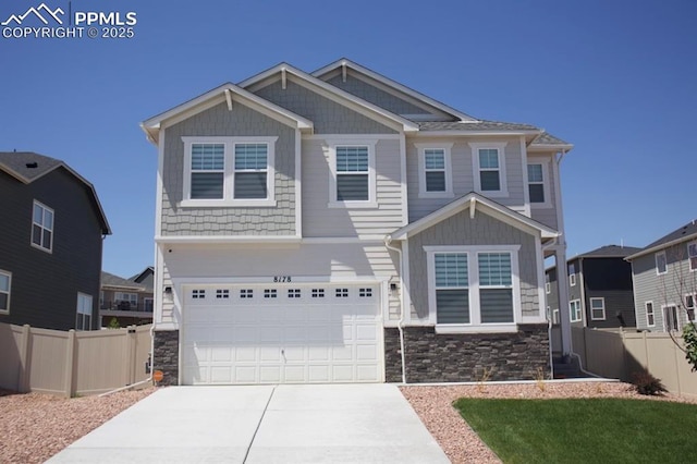 craftsman house featuring a garage, stone siding, fence, and concrete driveway