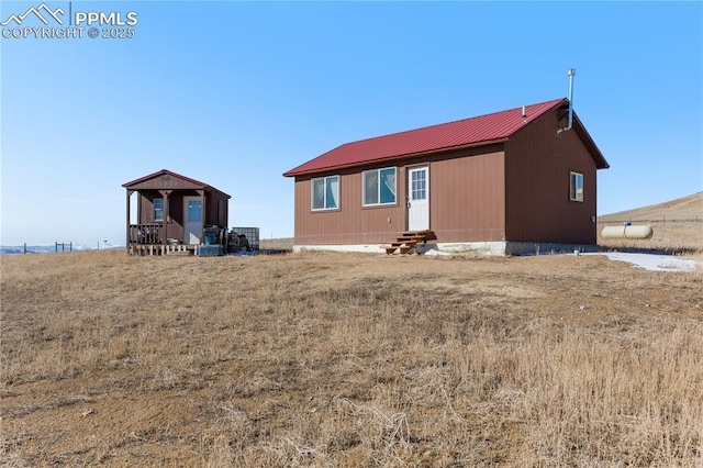 rear view of house with entry steps and metal roof