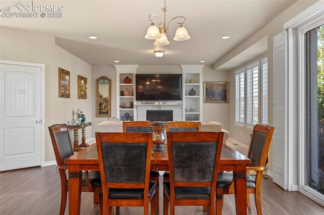 dining area with an inviting chandelier, a fireplace, baseboards, and wood finished floors