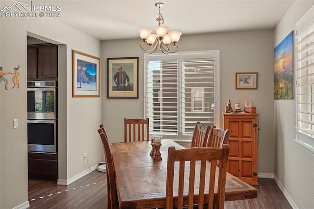 dining space featuring baseboards, dark wood-type flooring, and an inviting chandelier