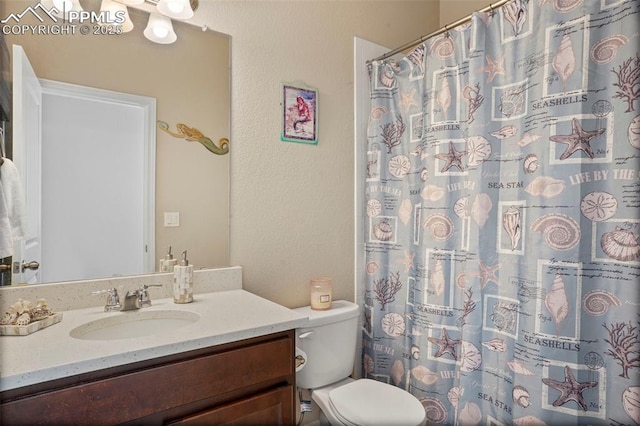 full bath featuring curtained shower, toilet, vanity, and a textured wall