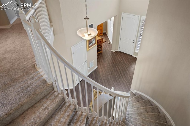 stairs with visible vents, baseboards, and a towering ceiling