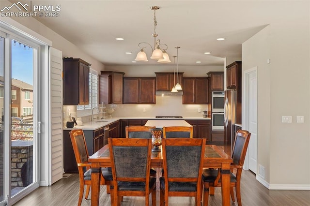 kitchen with tasteful backsplash, appliances with stainless steel finishes, dark wood-style floors, and light countertops