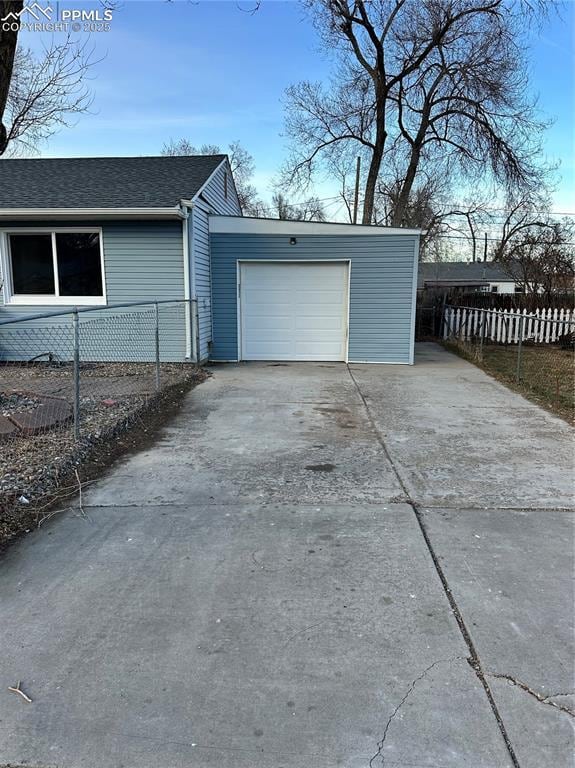 garage featuring driveway and fence