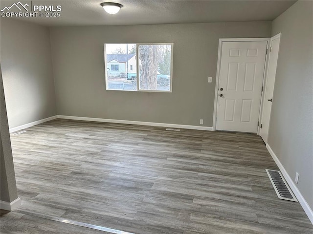 spare room featuring visible vents, baseboards, and wood finished floors