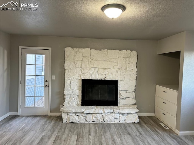 details with a fireplace, a textured ceiling, baseboards, and wood finished floors