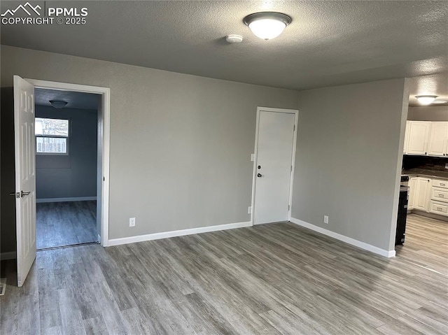 unfurnished room with baseboards, a textured ceiling, and light wood finished floors