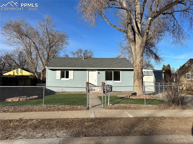 view of front of house with a shingled roof, a fenced front yard, a front yard, and a gate