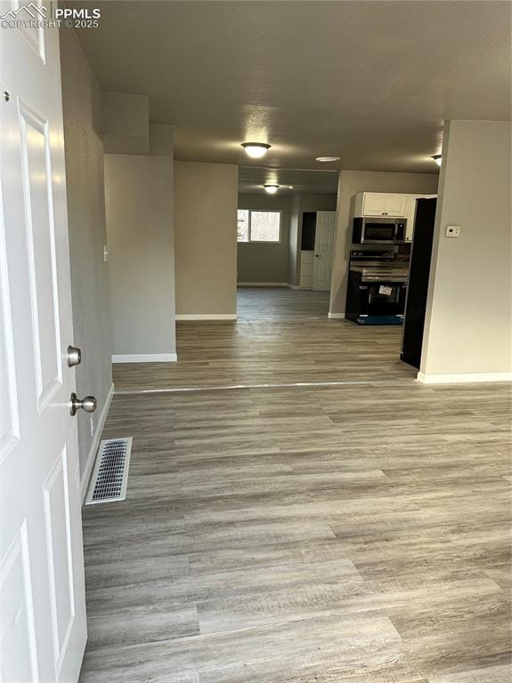 spare room featuring light wood-type flooring, baseboards, and visible vents