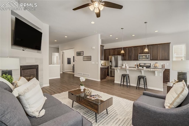 living area featuring a fireplace, wood finished floors, visible vents, and recessed lighting