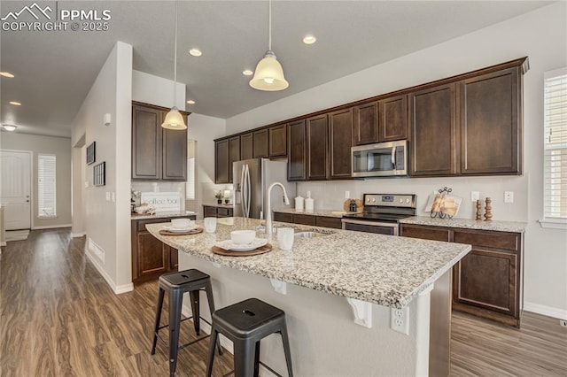 kitchen featuring dark brown cabinetry, a breakfast bar area, stainless steel appliances, and a sink