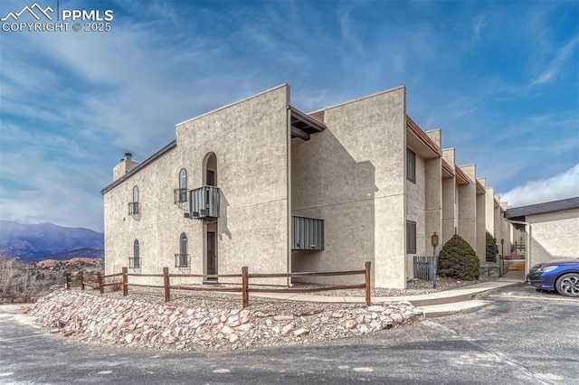 view of home's exterior with uncovered parking, fence, and stucco siding