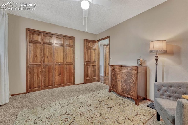 interior space with a textured ceiling, ceiling fan, carpet flooring, and baseboards