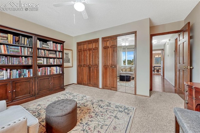 sitting room featuring a textured ceiling, carpet floors, and ceiling fan