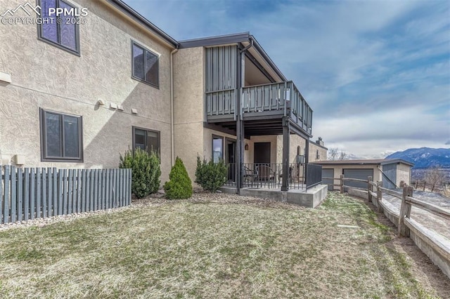 back of house featuring a patio, a balcony, fence, a mountain view, and stucco siding