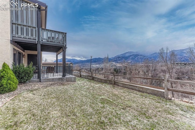 view of yard featuring a patio area, a fenced backyard, a mountain view, and a balcony