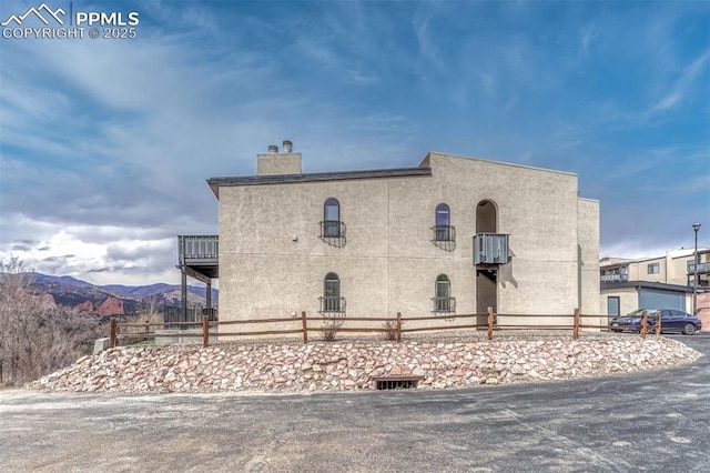 view of home's exterior featuring a mountain view, fence, and stucco siding