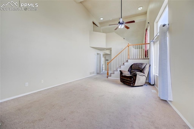 living room featuring ceiling fan, carpet floors, a towering ceiling, baseboards, and stairway