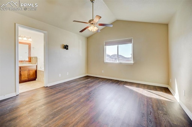 unfurnished room with vaulted ceiling, a sink, dark wood finished floors, baseboards, and ceiling fan