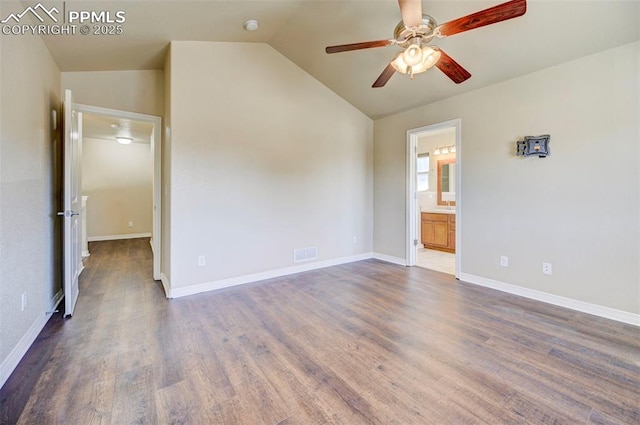 unfurnished bedroom featuring connected bathroom, vaulted ceiling, wood finished floors, baseboards, and visible vents