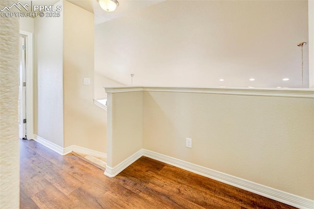 corridor featuring baseboards and wood finished floors