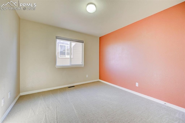 unfurnished room with baseboards, visible vents, and carpet