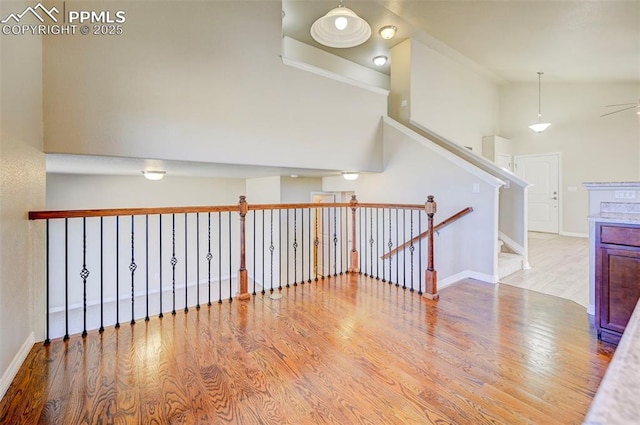 unfurnished room with baseboards, high vaulted ceiling, wood finished floors, and ceiling fan