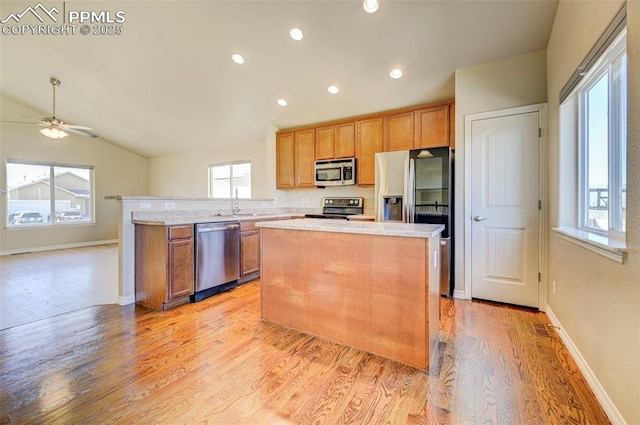 kitchen featuring a ceiling fan, light wood finished floors, a center island, lofted ceiling, and stainless steel appliances